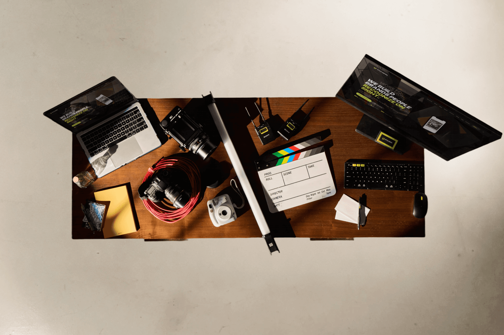 Style Driven creative tools laid out on a walnut desk with laptop, cinema camera, clapperboard, audio gear, monitor