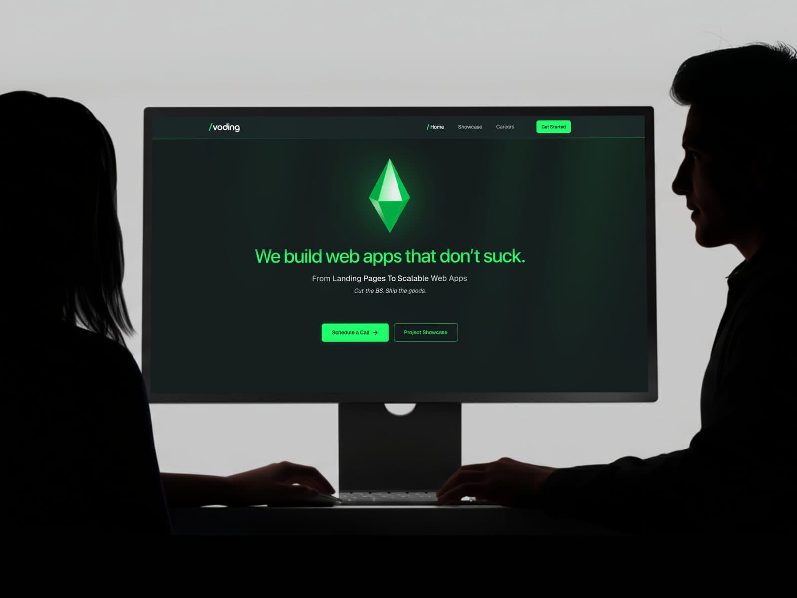 Two people at a monitor, reviewing a live build of the Voding site.
